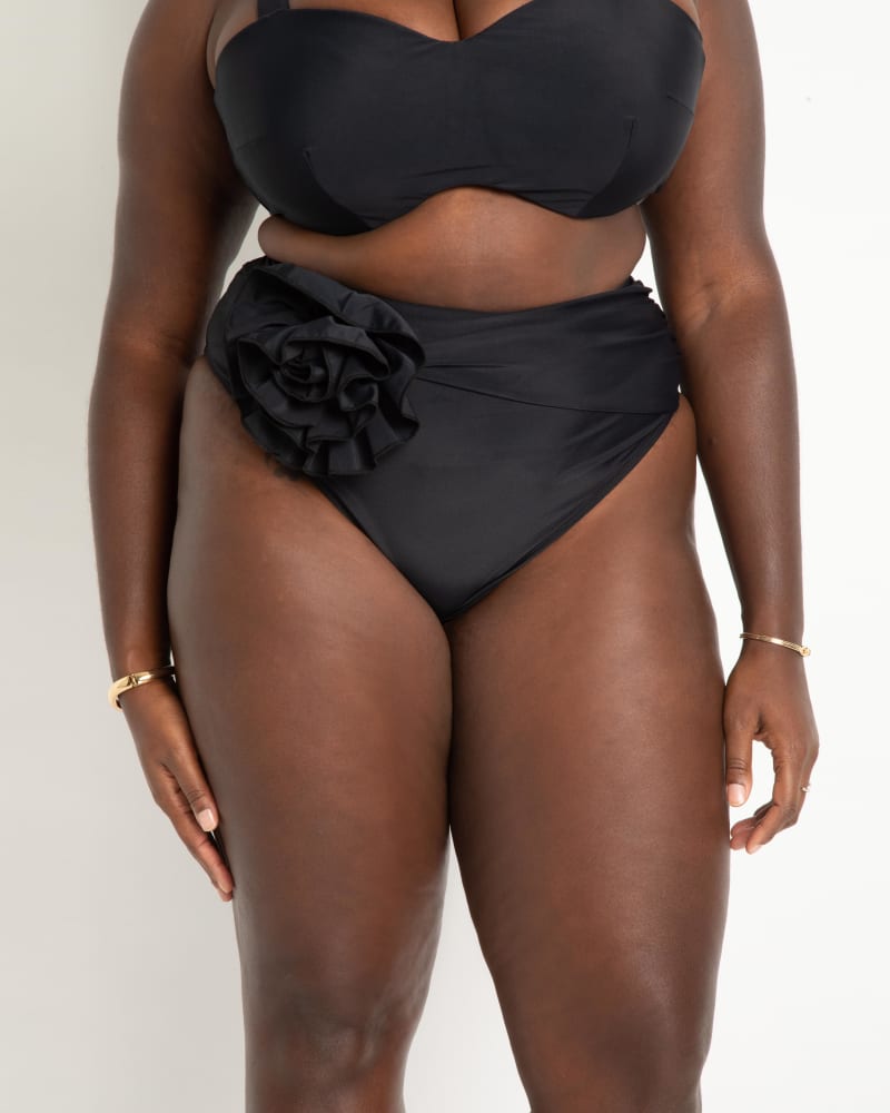 Front of a model wearing a size 28 High Waisted Bikini Bottom with Rosette in Black by ELOQUII. | dia_product_style_image_id:272797